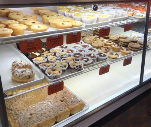 A display case filled with various baked goods, including muffins, cookies, and pastries.