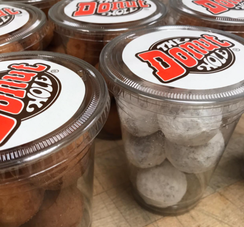 Clear plastic containers filled with donut holes, some plain and some powdered, labeled "The Donut Hole."