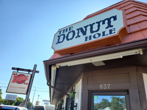 Sign for "The Donut Hole" with a clear blue sky in the background, featuring a nearby "Double D" sign.