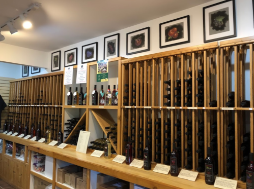 A wine shop interior featuring wooden racks filled with bottles and framed fruit photos on the walls.