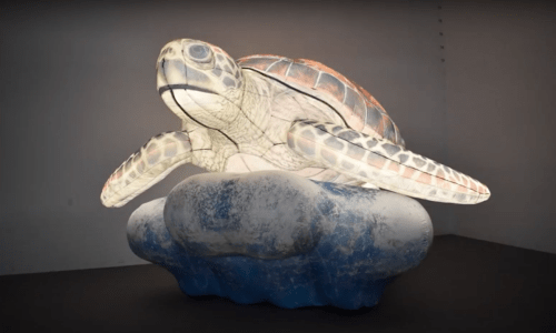 A large, illuminated turtle sculpture resting on a cloud-shaped base, showcasing intricate details and vibrant colors.