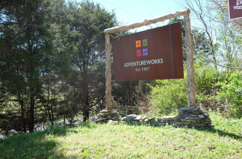 Sign for AdventureWorks, established in 1987, surrounded by greenery and trees.