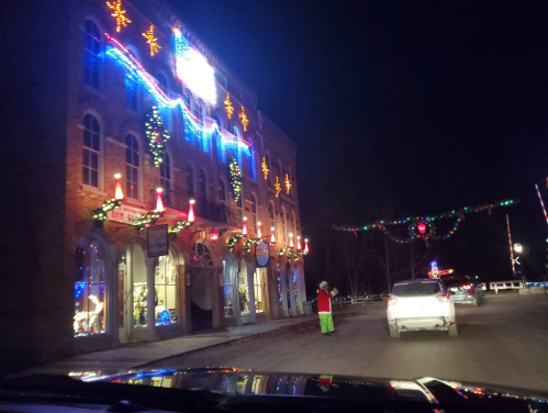 A festive building adorned with colorful lights and decorations at night, with a person in a Santa costume nearby.