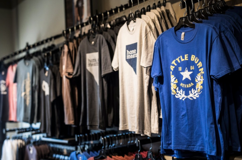 A display of various t-shirts hanging on racks in a store, featuring different colors and designs.