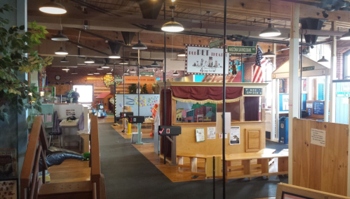 Interior of a vibrant indoor play area with colorful displays, benches, and various activity stations.