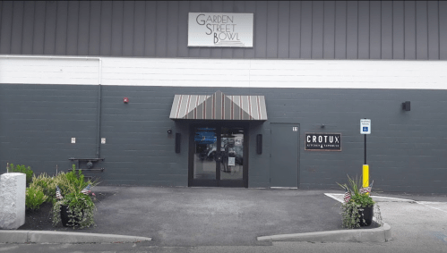 Exterior of Garden Street Bowl with a striped awning, entrance doors, and planters with American flags.