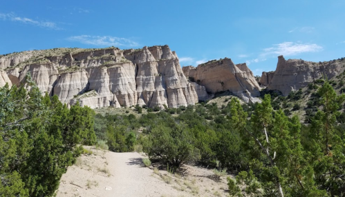 A scenic view of layered rock formations and green shrubs under a clear blue sky.