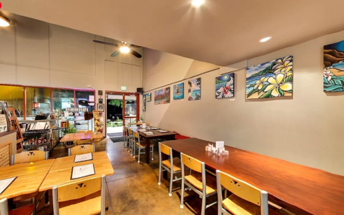 Interior of a cozy restaurant featuring wooden tables, colorful artwork on the walls, and a welcoming atmosphere.