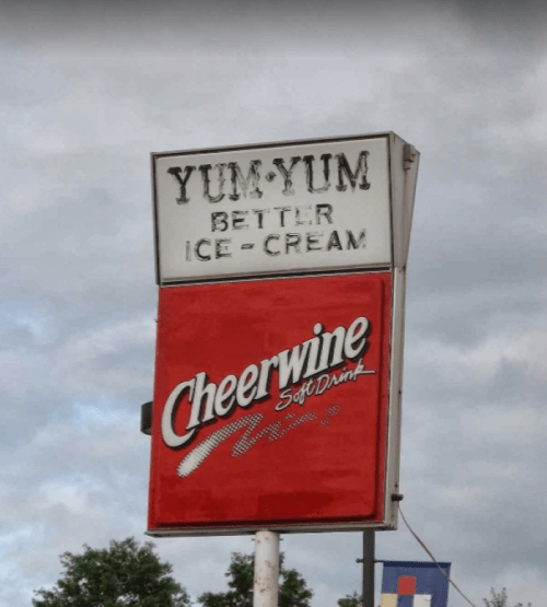 Sign for Yum Yum Ice Cream featuring Cheerwine soft drink, with a cloudy sky in the background.