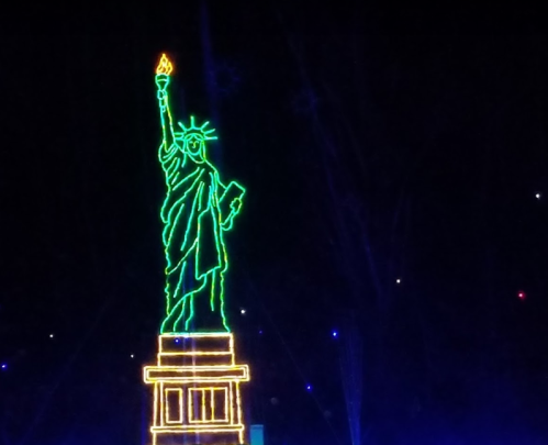 Neon outline of the Statue of Liberty against a dark background, with a flame atop her torch illuminated.