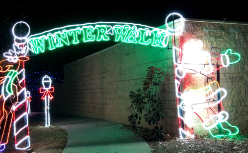 A festive archway reading "Winter Walk" with colorful lights, featuring Santa and a reindeer on either side.