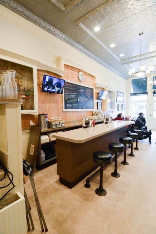 A cozy café interior featuring a long counter with stools, chalkboard menus, and a warm, inviting atmosphere.