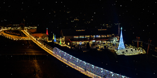 A festive scene at night featuring a building and pathways adorned with colorful Christmas lights and decorations.