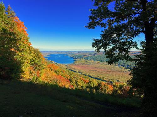 A scenic view of a river surrounded by vibrant autumn foliage under a clear blue sky.
