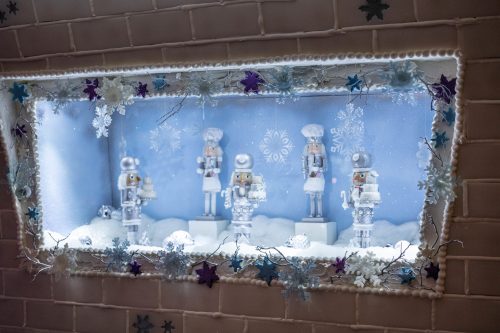 A festive display featuring five nutcracker figures in a snowy scene, surrounded by white and blue decorations.