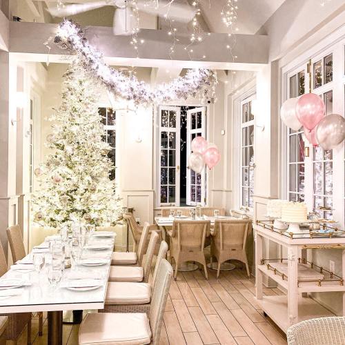 A beautifully decorated dining area with a white Christmas tree, balloons, and a festive table setting.