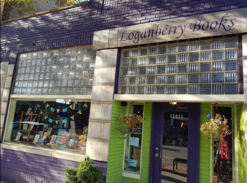 Exterior of Loganberry Books, featuring purple and green walls, large glass block windows, and a welcoming entrance.