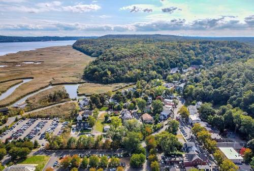 Aerial view of a scenic landscape with a river, wooded hills, and a small town surrounded by greenery and parking areas.