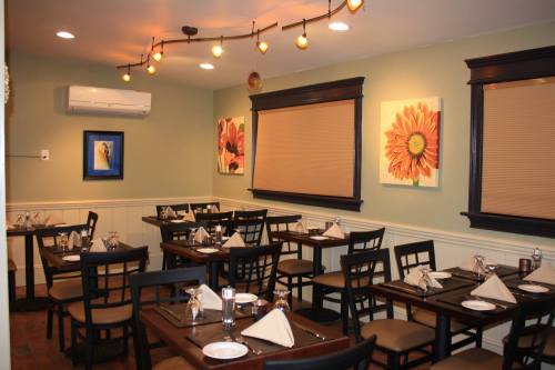 Cozy restaurant interior with wooden tables, chairs, and floral artwork on the walls, featuring soft lighting.