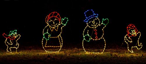 Colorful holiday light decorations of snowmen and a small snowchild waving in the dark.