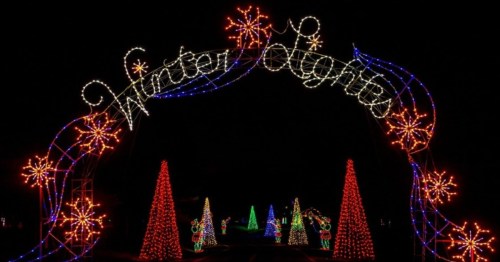 Colorful holiday lights form an arch reading "Winter Lights," with decorated trees and snowflakes in a dark setting.
