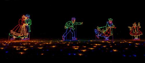 Colorful holiday lights depict a couple dancing and children playing in a festive outdoor scene.