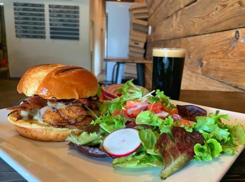A delicious burger with bacon and cheese, served with a fresh salad and a glass of dark beer on a wooden table.