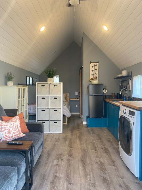 Cozy interior of a small home with a living area, kitchen, and laundry, featuring modern decor and natural light.