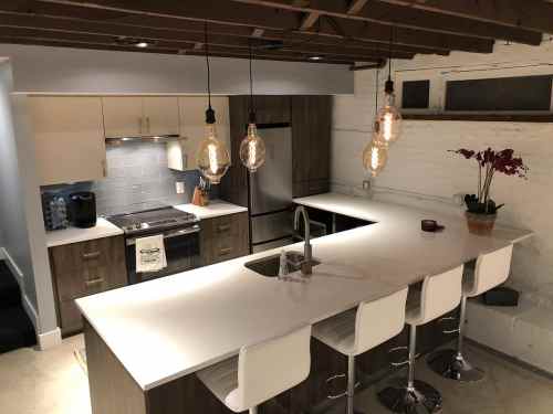 Modern kitchen with a large island, pendant lights, stainless steel appliances, and a minimalist design.