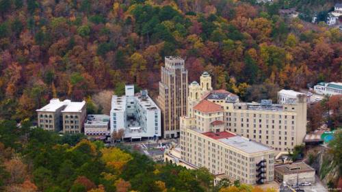 Aerial view of a historic hotel complex surrounded by colorful autumn foliage in a mountainous area.