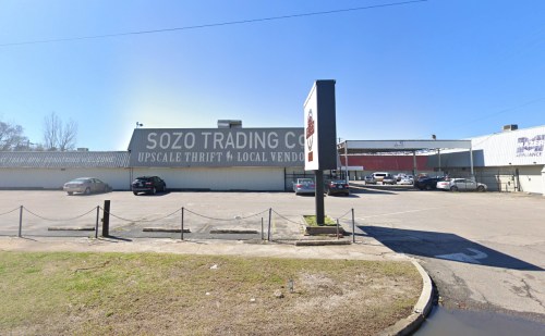 Exterior view of Sozo Trading Co. with a parking lot and clear blue sky. Signage indicates it's an upscale thrift store.