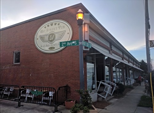 Exterior of 41st Street Pub, featuring a sign and street corner with outdoor seating and a warm evening glow.