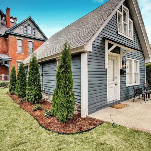 A charming gray house with a sloped roof, surrounded by green shrubs and a well-maintained lawn.