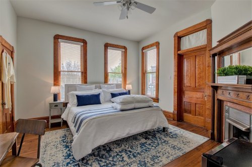 Cozy bedroom with a bed, decorative pillows, wooden accents, and large windows letting in natural light.
