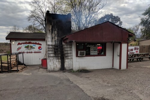 A small restaurant with a red roof and smoke rising from the chimney, featuring an "Open" sign in the window.