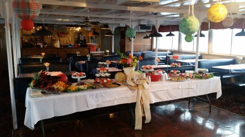 A decorated dining area with a buffet table filled with various dishes, desserts, and colorful lanterns hanging above.