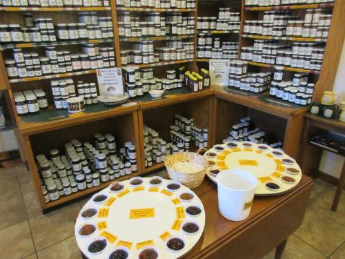 A cozy shop interior with shelves of jars and two tasting trays of various spreads on a wooden table.