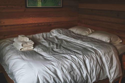 A neatly made bed with a white comforter and two pillows, accompanied by folded towels on top.