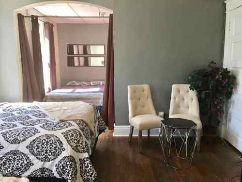 Cozy bedroom with a bed, two chairs, a small table, and a doorway leading to another room.