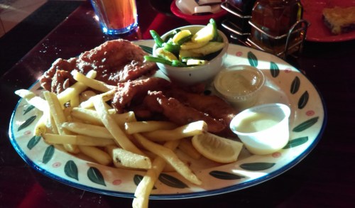 A plate of fried chicken strips, French fries, a small bowl of mixed vegetables, and dipping sauces.