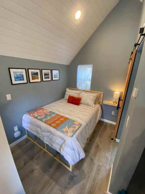 Cozy bedroom with a sloped ceiling, featuring a bed, decorative pillows, and framed pictures on the wall.