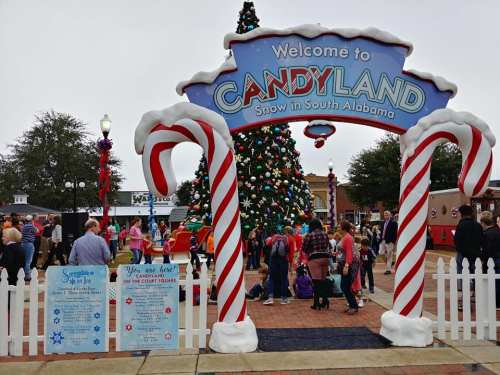 A festive entrance to Candyland in South Alabama, featuring a decorated Christmas tree and crowds enjoying the holiday atmosphere.