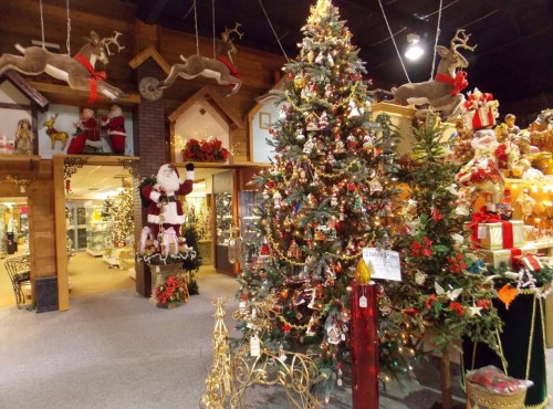A festive holiday display featuring a decorated Christmas tree, Santa figure, and various ornaments in a cozy shop.