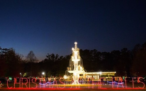 A beautifully lit Christmas display featuring a fountain and the words "Christmas Lights" in bright colors at dusk.