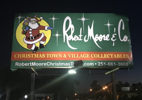 Billboard advertising Robert Moore & Co. with Santa Claus, promoting Christmas town and village collectibles.