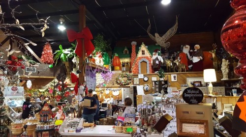 A festive shop filled with holiday decorations, ornaments, and displays, with shoppers browsing among colorful items.