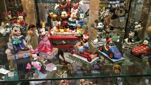 A display case filled with various Disney figurines, including Mickey and Minnie Mouse in different outfits and scenes.