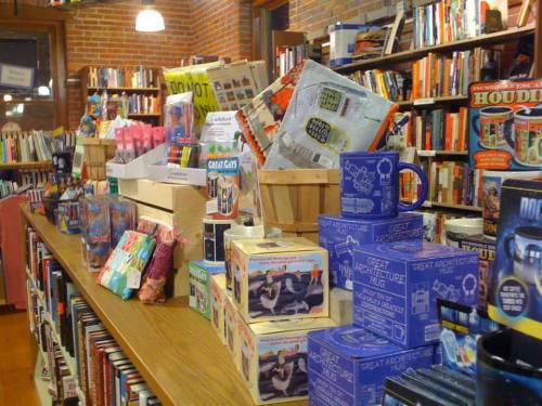 A cozy bookstore display featuring colorful merchandise, books, and unique gift items on wooden shelves.