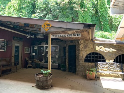 Entrance to an underground mine tour, featuring a sign and rustic decor surrounded by greenery.