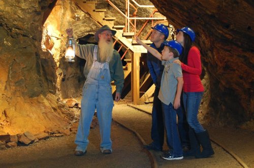 A guide with a lantern shows a family in a mine, as they explore the underground environment together.